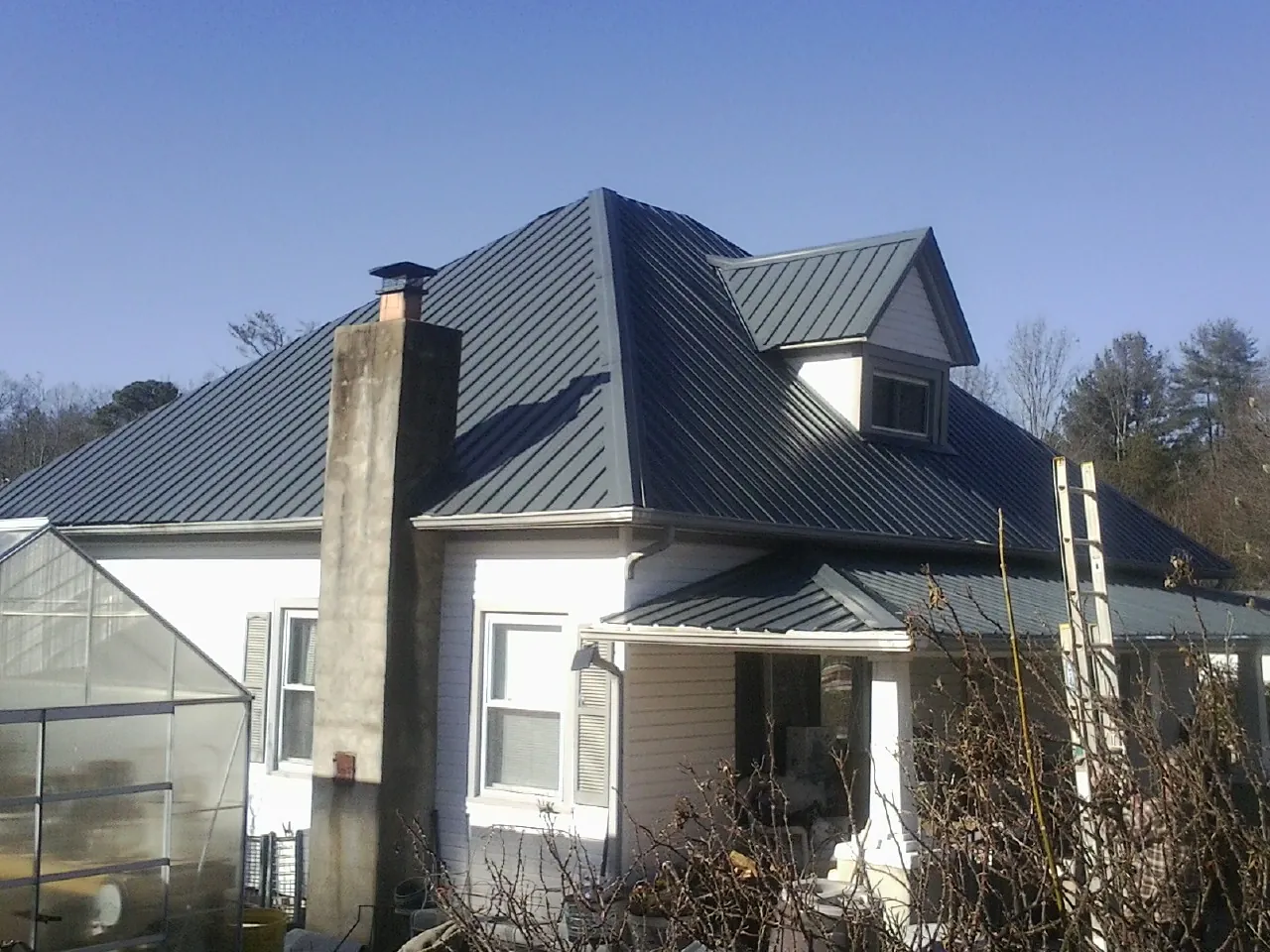 Dark blue standing seam metal roof on a white farmhouse with dormer — Slate & Tile Roof Repair by Roofing Brothers in Hastings