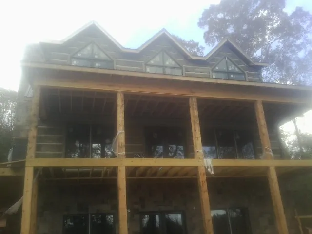 Dormers and porch framing on a large log home under construction — Roof Coating work by our crew in Hastings